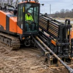 Trenchless Drilling Machine Ground Selection Guide Orange tracked trenchless drilling machine with drill rods at a roadside bore