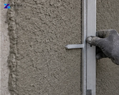 Worker measuring applied mortar thickness on a wall