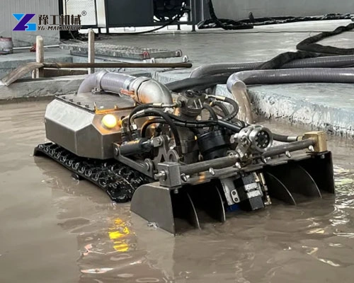 Tracked dredging unit with front intake and hydraulic hoses in shallow water